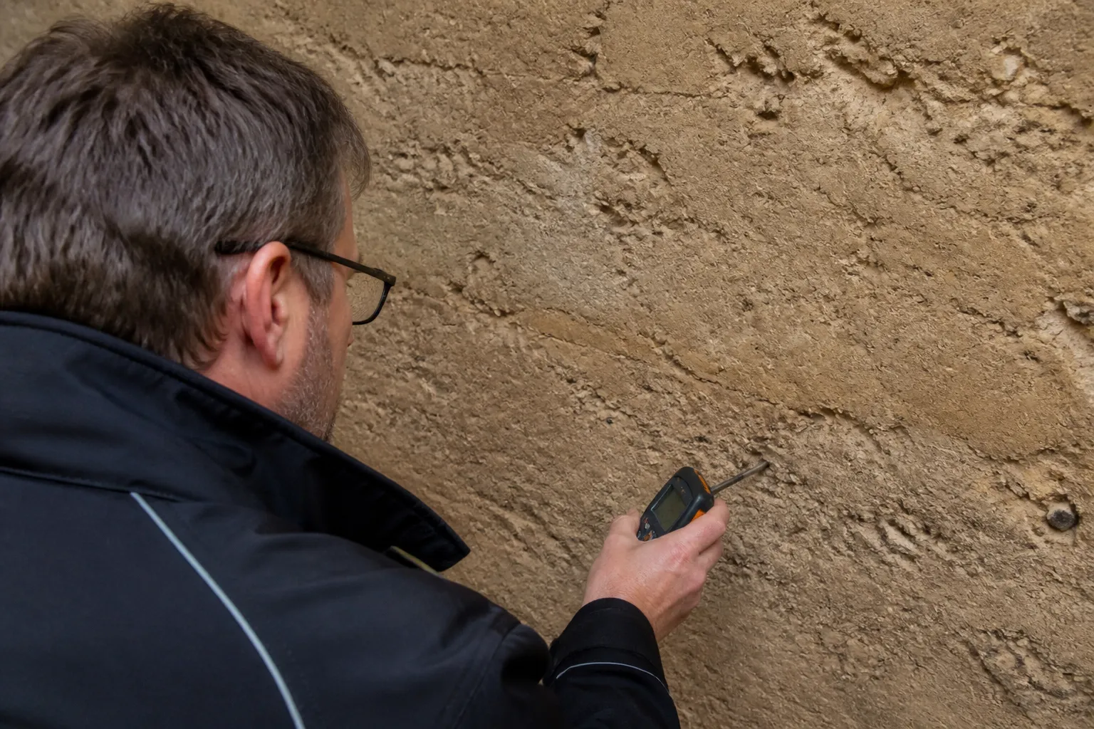 Expert sondant un mur en pise avec un humidimetre